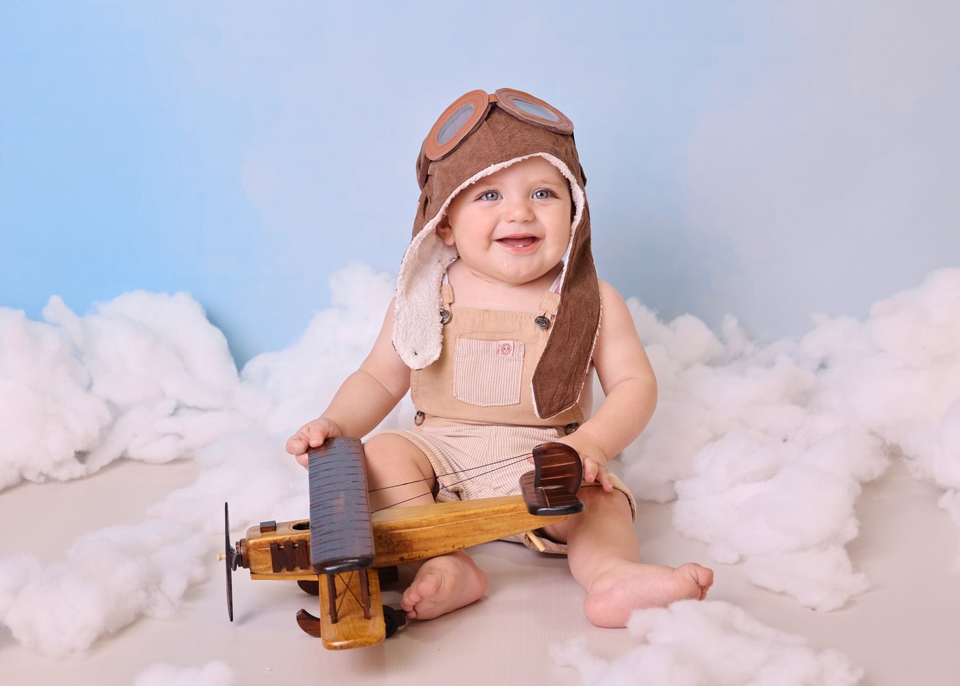 Baby pilot with a wooden plane in the clouds