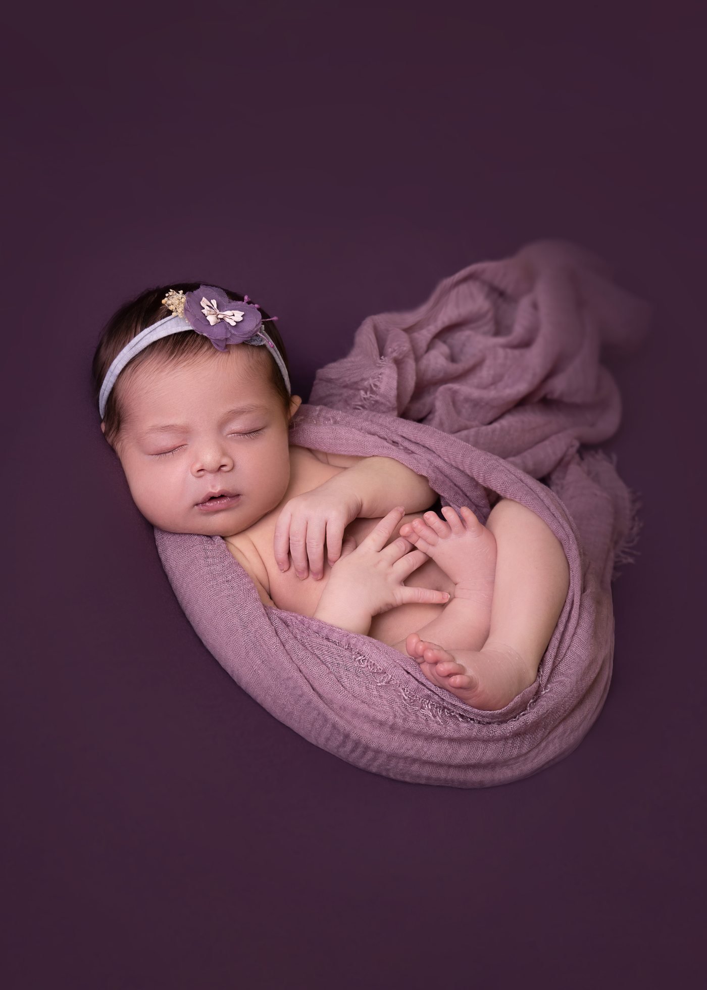 Newborn sleeping, wrapped in soft lilac